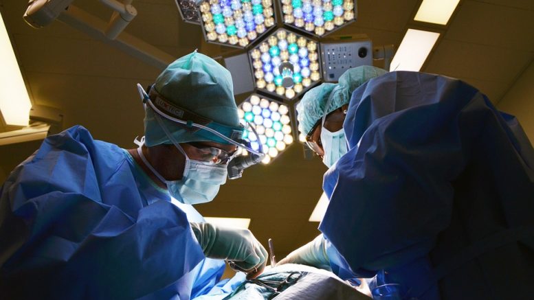 Surgeons placing artificial wearable organ