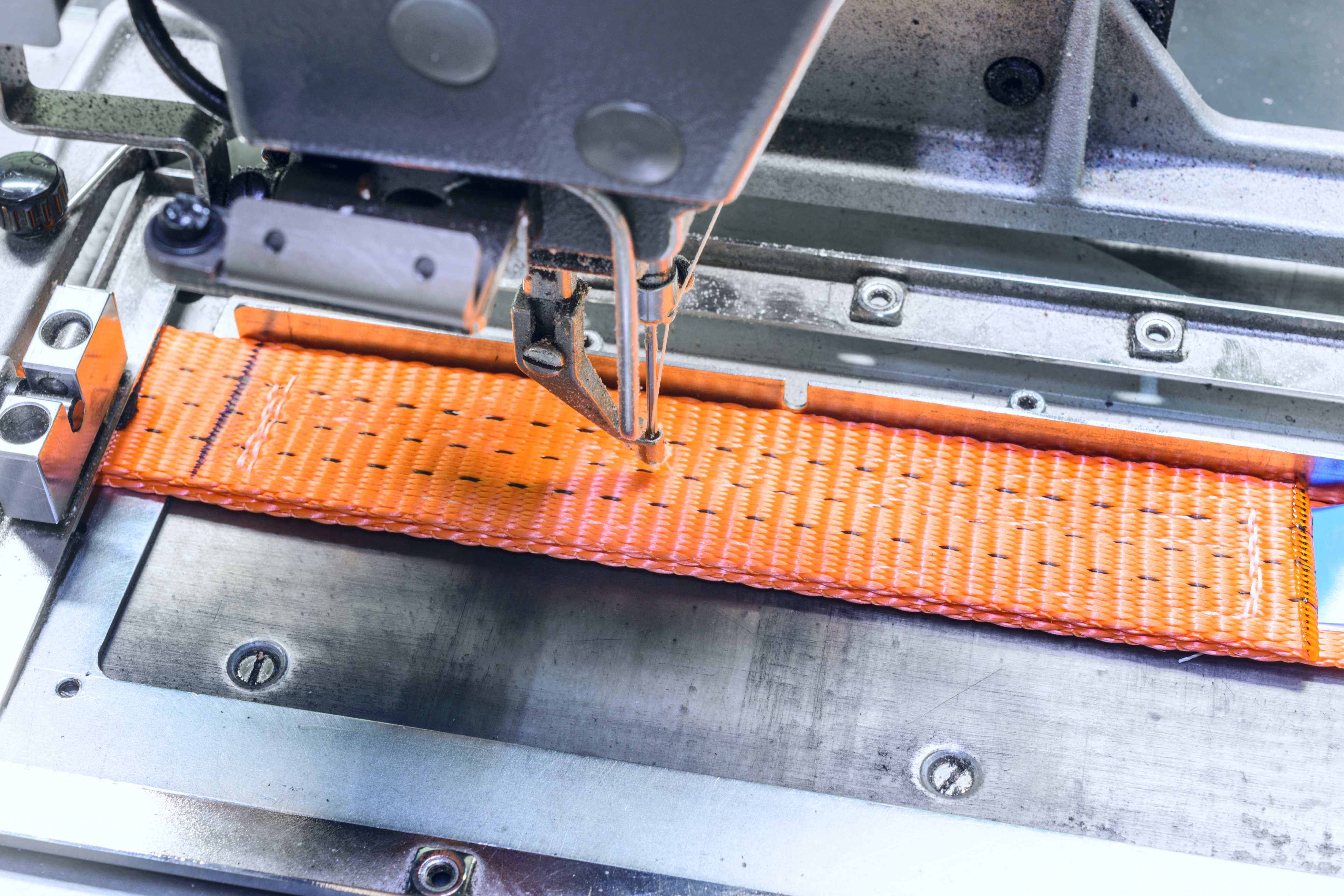 Orange Polyester strapping being in a sewing machine